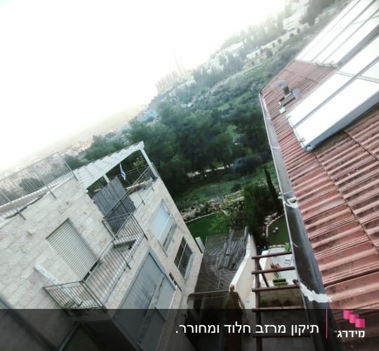גג רעפים עם קולטי שמש ומעקה מתכת